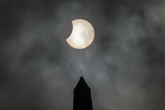 The sun breaks through clouds during a partial solar eclipse visible over Stoodley Pike, a 1,300ft hill in West Yorkshire (Danny Lawson/PA)