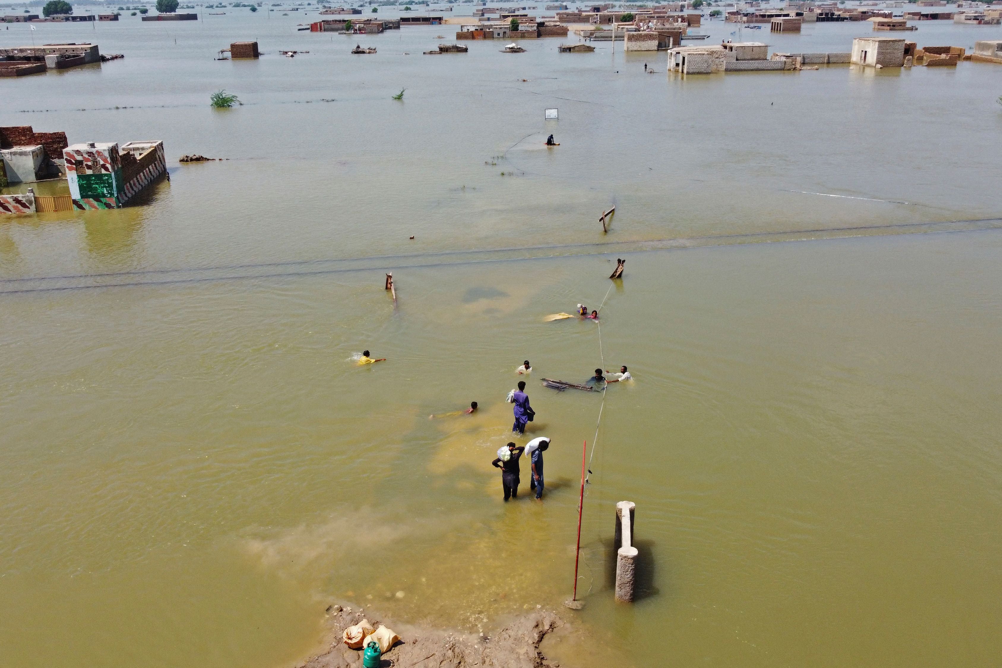 People wade through a submerged area of Balochistan province in Pakistan following the worst floods in the country’s history