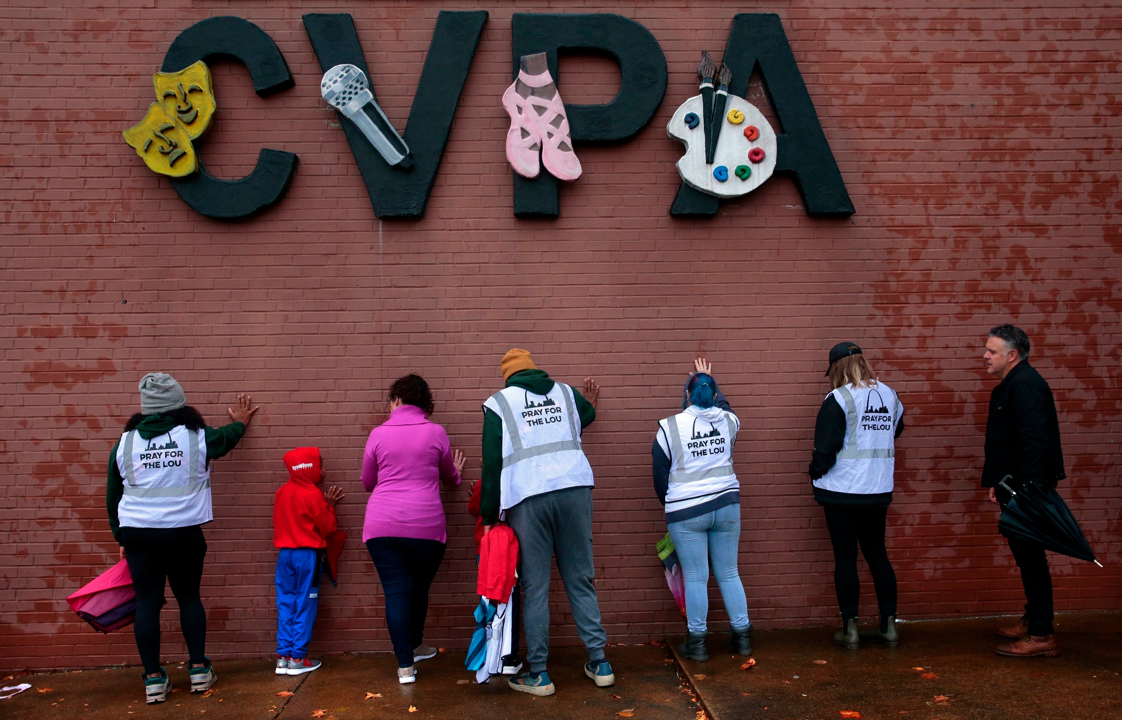 A group of visitors from the group "Pray for the Lou" place hands on the building during prayers at the site of a school shooting at Central Visual & Performing Arts High School in St. Louis, Tuesday, Oct. 25, 2022 in St. Louis