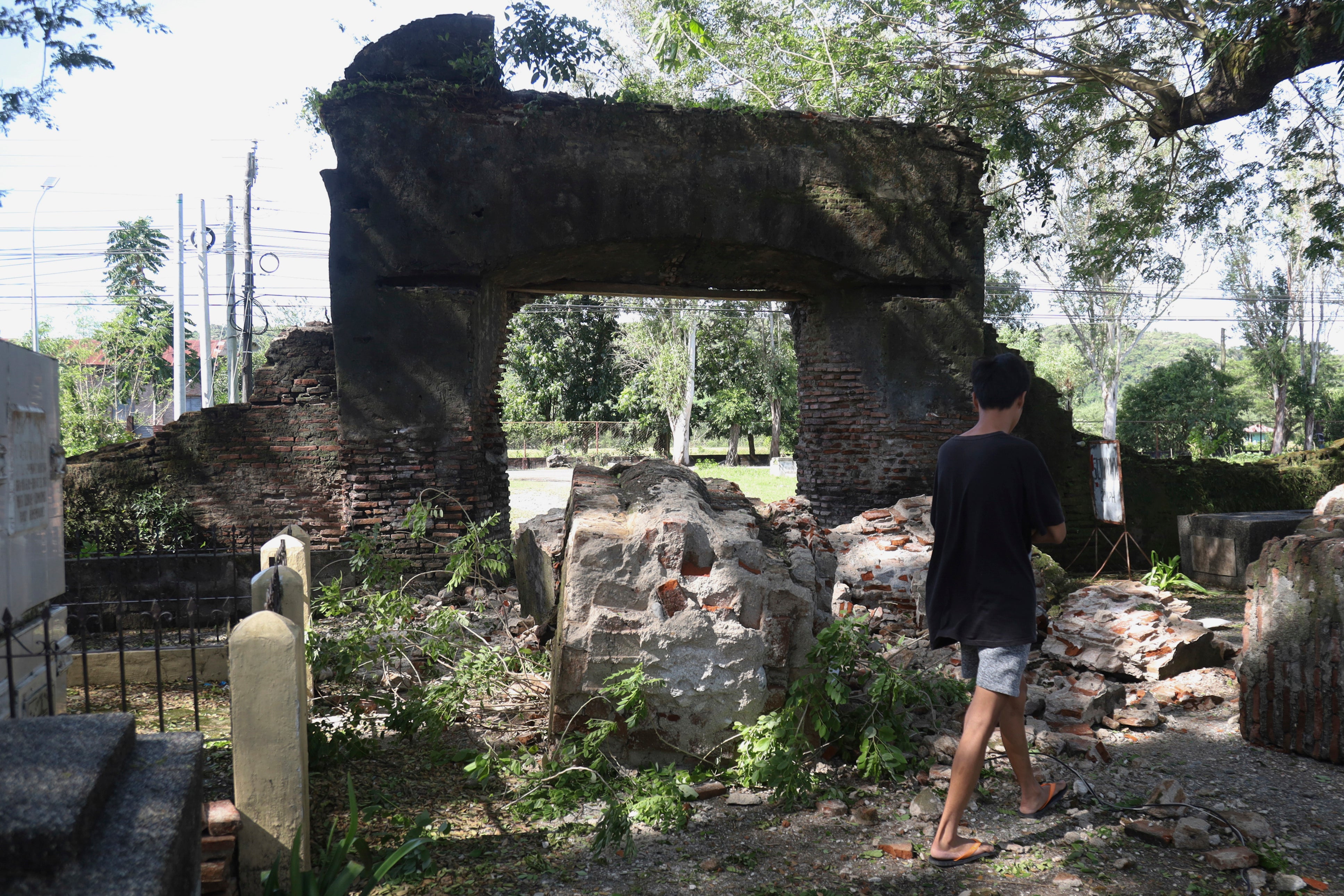 A man walks beside a damaged wall after a strong earthquake at Ilocos Norte, Northern Philippines