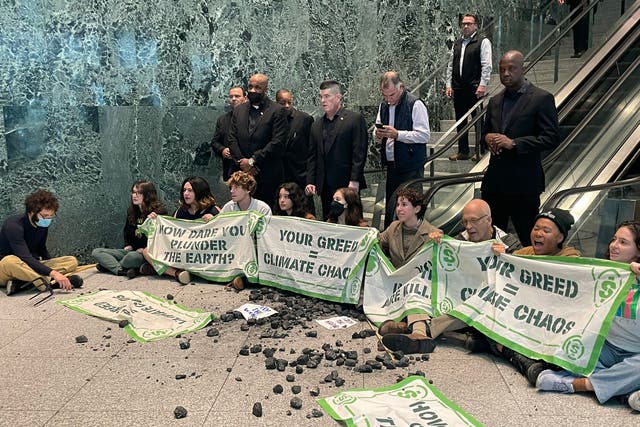 <p>Activists sit down in front of BlackRock’s escalators in New York on Wednesday</p>