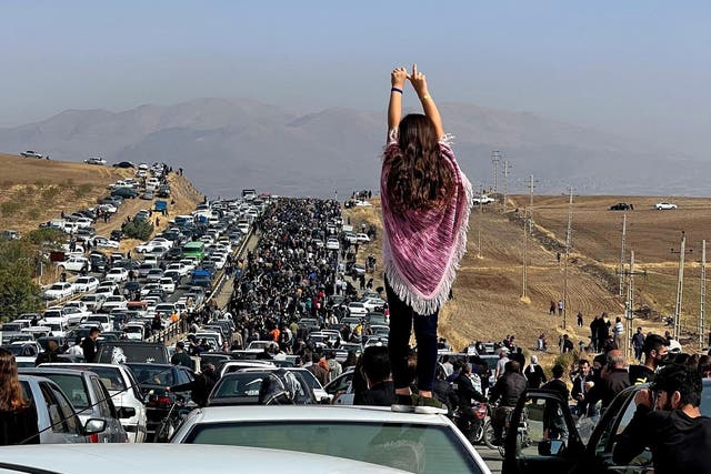 <p>A woman stands on top of a vehicle as thousands make their way towards Aichi cemetery in Saqez, Mahsa Amini’s home town in the western Iranian province of Kurdistan, to mark 40 days since her death</p>