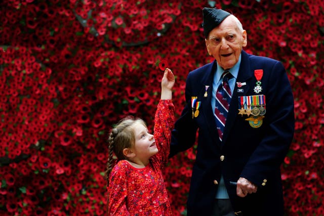 98-year-old D-Day Veteran Bernard Morgan, whose story is among those featured on the giant poppy wall, is given a poppy by Maya Renard, aged 6, during the launch of The Royal British Legion 2022 Poppy Appeal (Victoria Jones/PA)