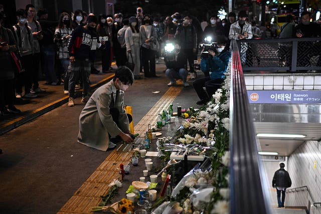 <p>A man pours a glass of an alcoholic beverage in tribute to those who were killed at a Halloween stampede late on 29 October in the district of Itaewon in Seoul on 30 October</p>
