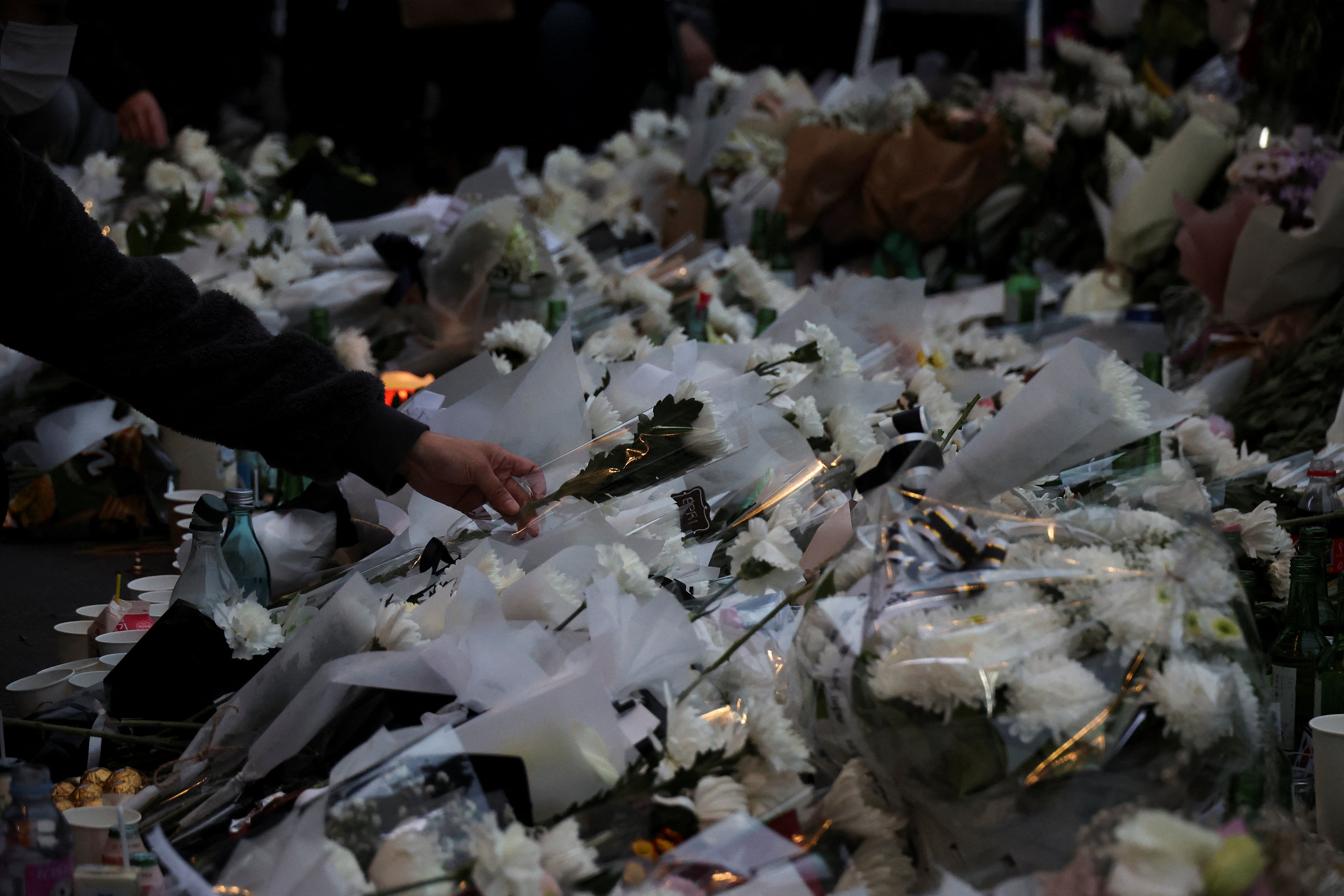 A mourner lays flowers at a tribute site for those killed in the stampede