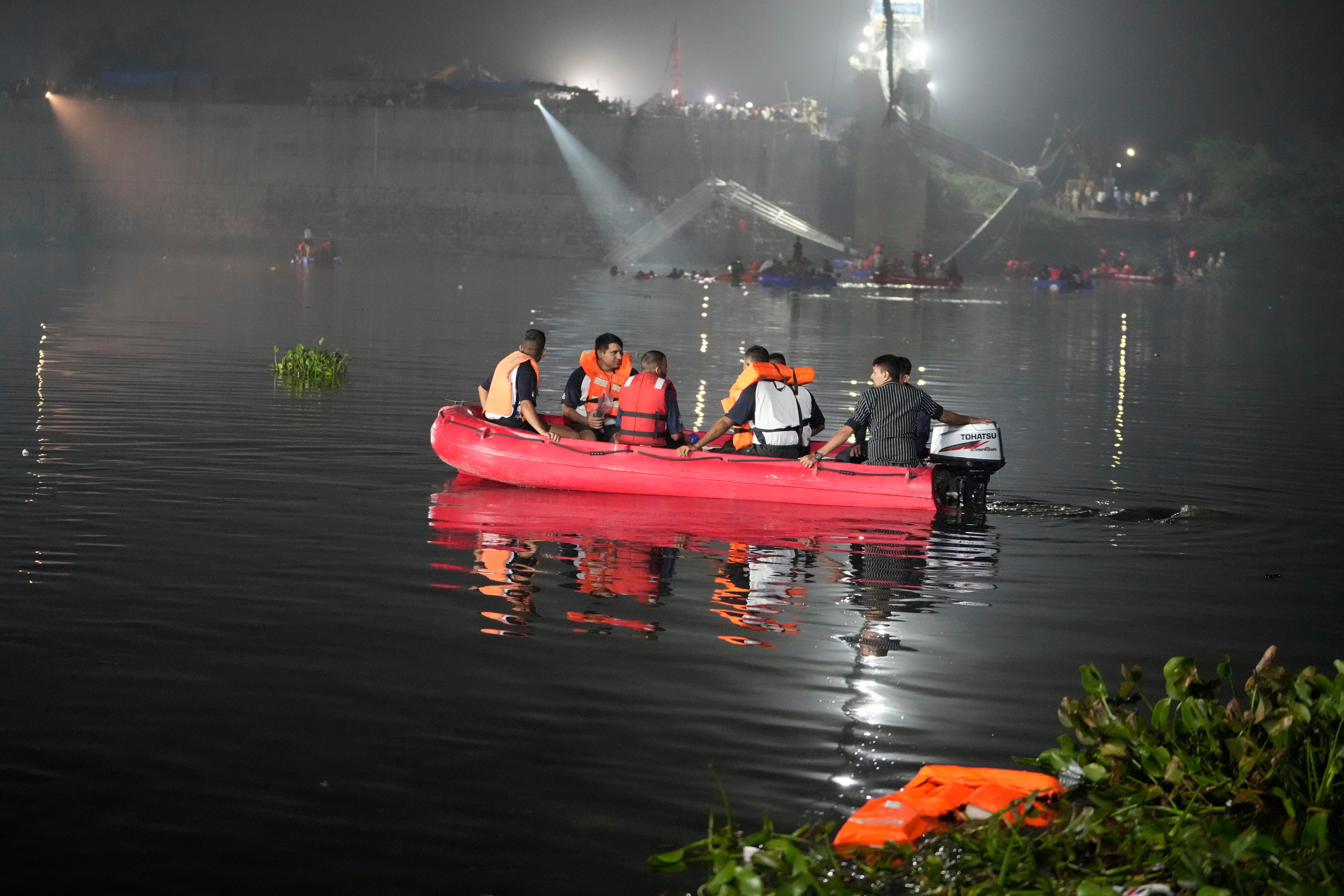 Rescuers on boats search in the Machchu river next to a cable bridge that collapsed in Morbi