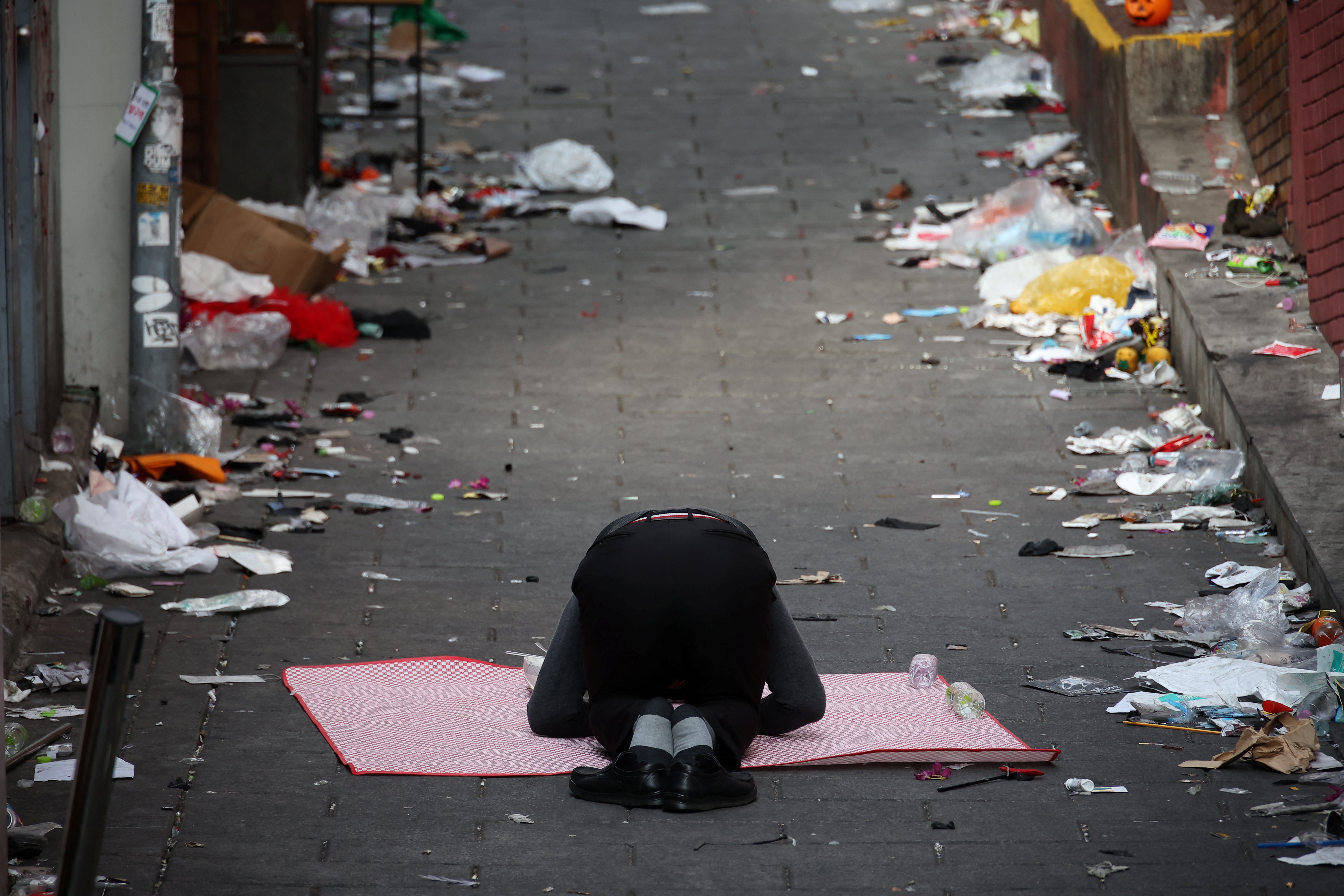 The clerk of a shop situated on the site where a stampede happened during Halloween festivities pays respects in the middle of the site