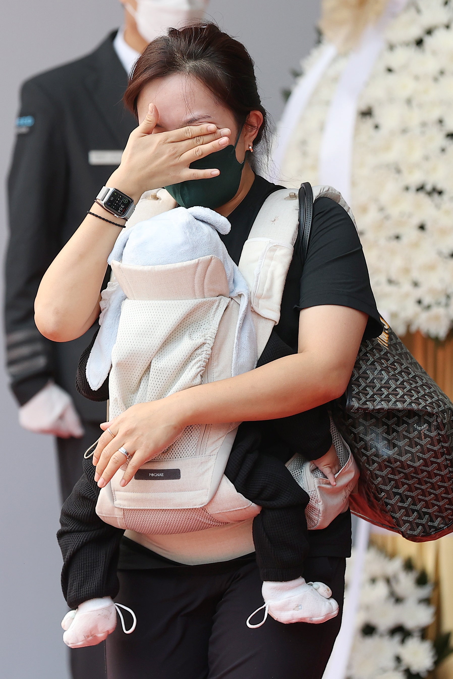 A woman carrying a baby cries at a memorial altar to the victims of a deadly stampede in Seoul