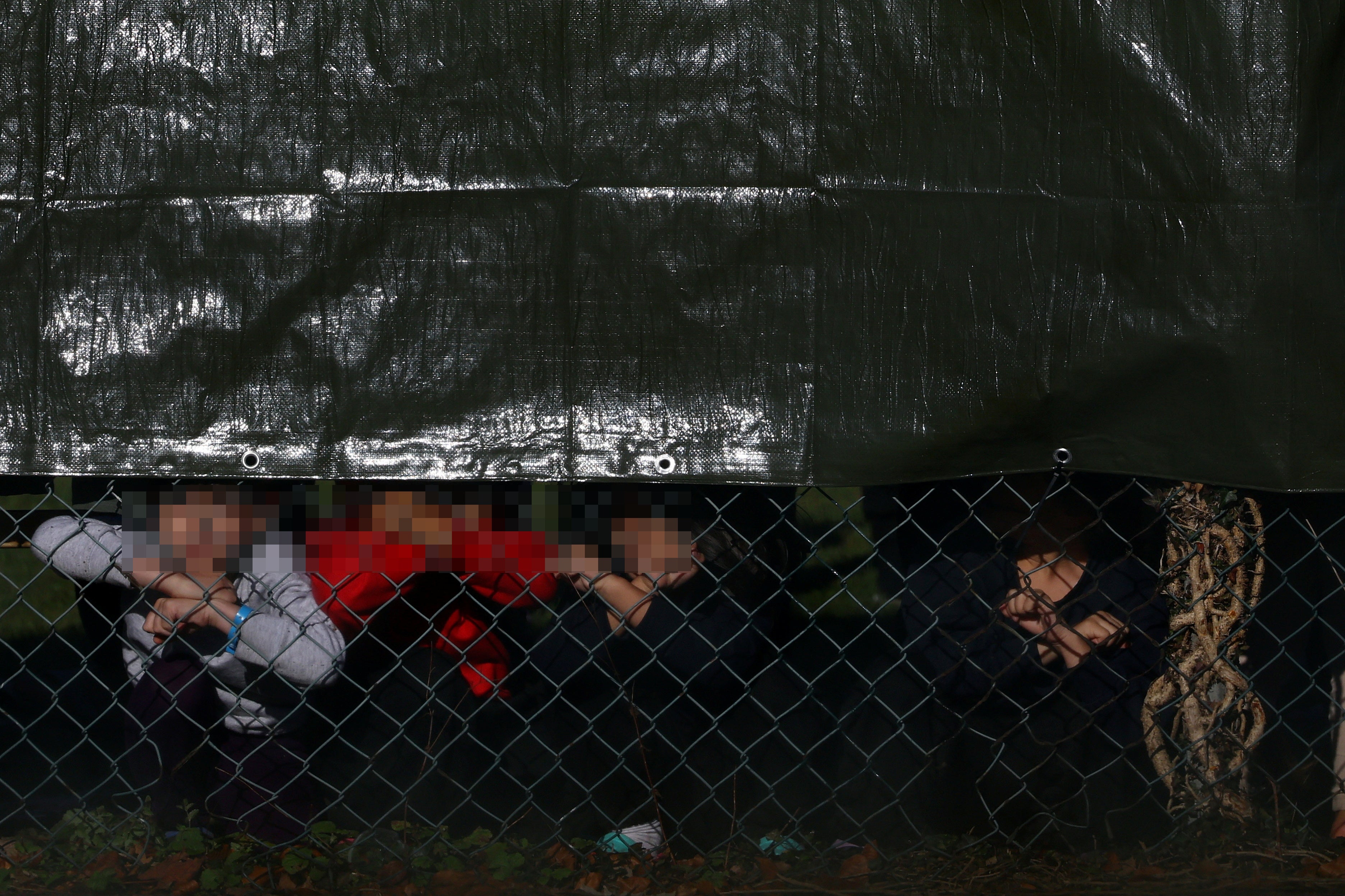 Child detainees look out a fence at Manston