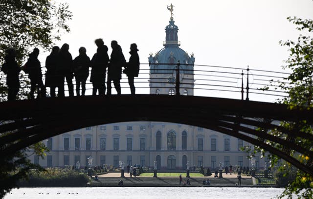 <p>People take a walk at the gardens at Charlottenburg Castle in Berlin on October 20, 2022. </p>