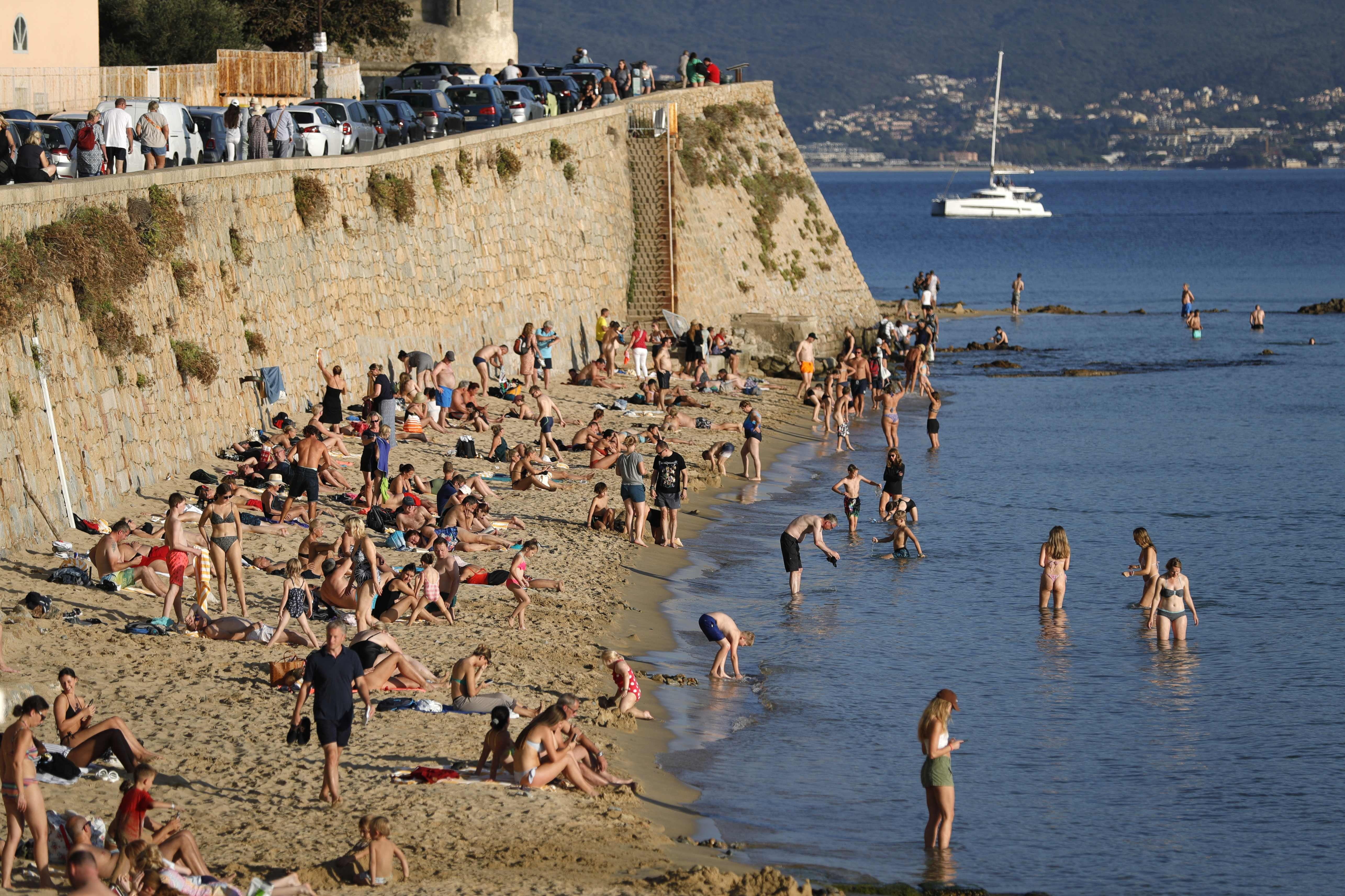 Local residents and tourists enjoy the warm weather at the Saint Francois beach in Ajaccio on the French Mediterranean island of Corsica on October 19, 2022.
