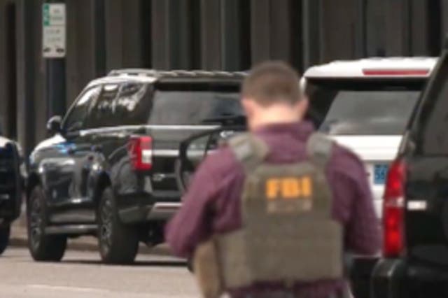 <p>An FBI agent stands in front of a standoff between police and a man in a car with a gun to his head</p>