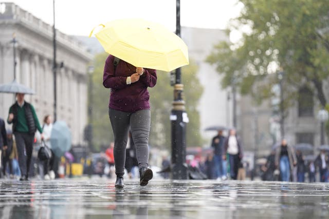 A woman shelters from the wet weather beneath an umbrella near Trafalgar Square, central London (James Manning/PA)