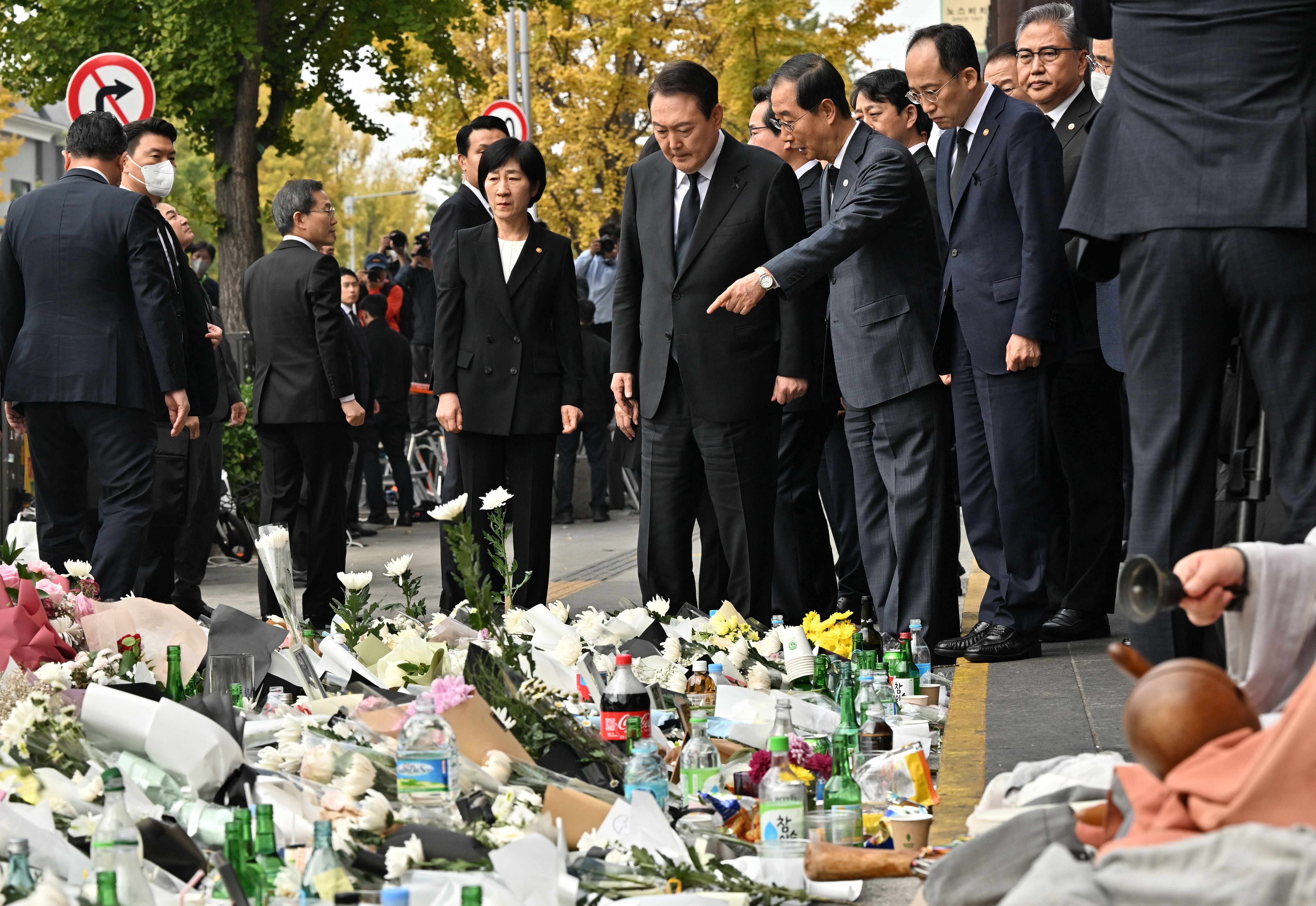 South Korean president Yoon Suk-yeol speaks with prime minister Han Duck-soo (centre R) as they visit a makeshift memorial for the victims of the deadly Halloween crowd surge, outside a subway station in the district of Itaewon in Seoul on 1 November 2022