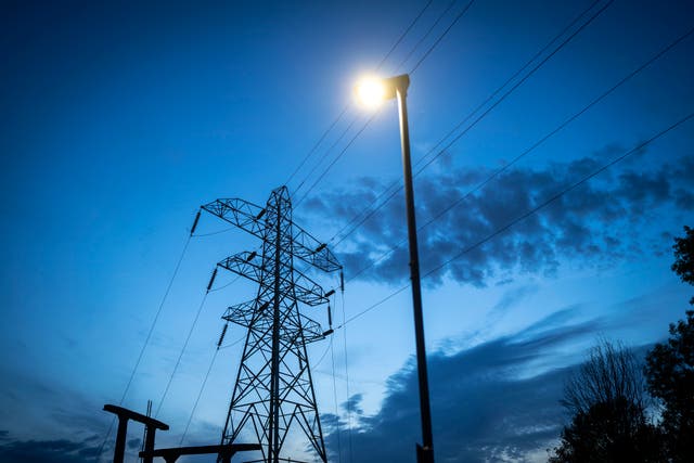 <p>Night falls behind electricity pylons and a sub station in Manchester</p>