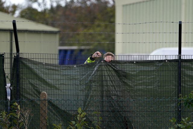 A member of security staff secures screens around the Manston immigration short-term holding facility located at the former Defence Fire Training and Development Centre in Thanet, Kent (Gareth Fuller/PA)