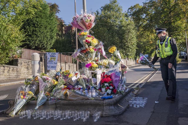 A police community support officer lays a floral tribute at the scene in Woodhouse Hill (Danny Lawson/PA)