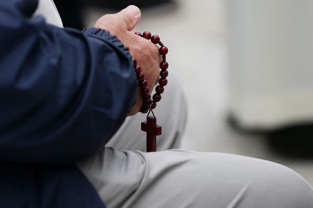File photo of a man holding rosary beads (Brian Lawless/PA)