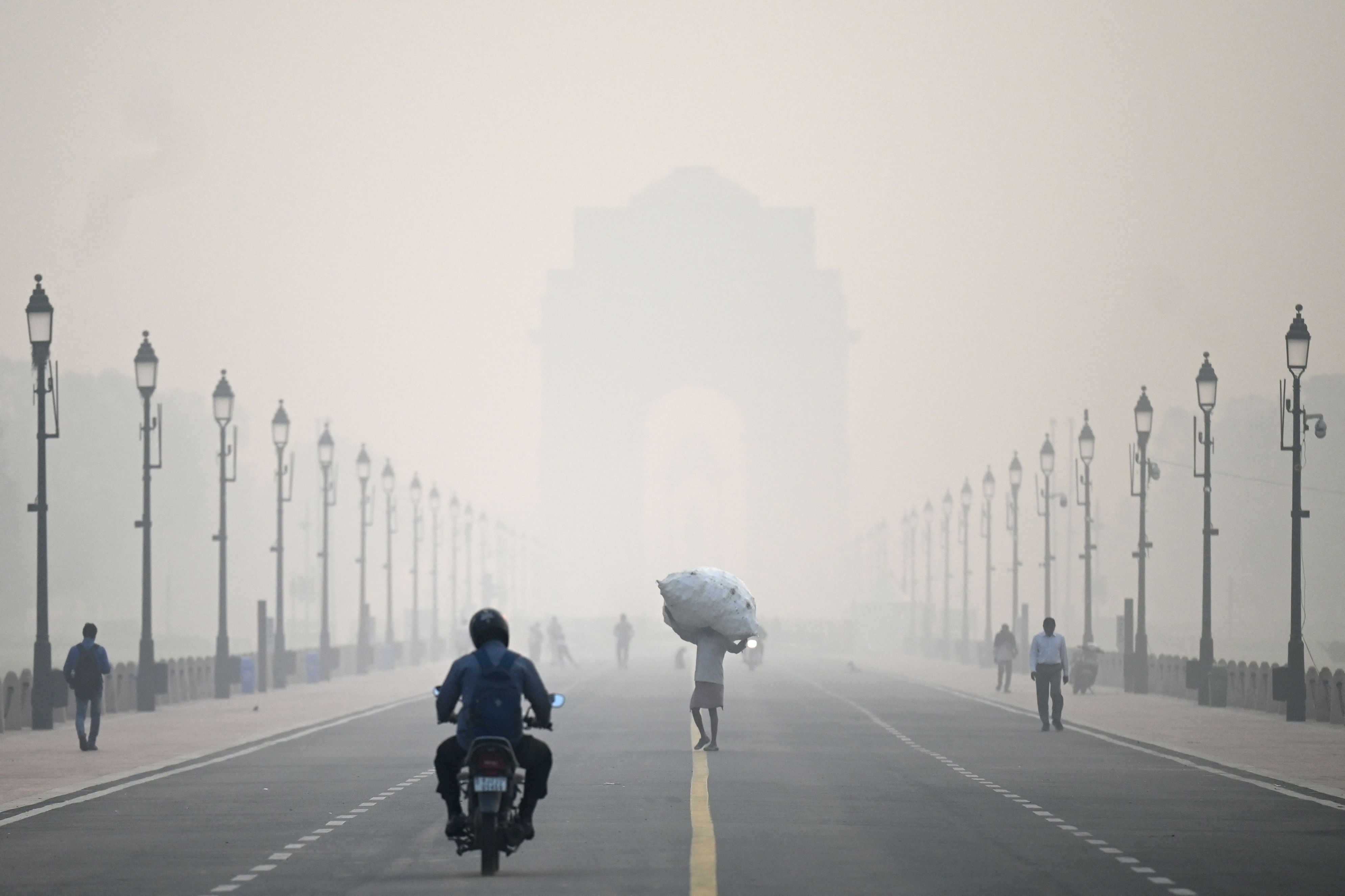 A man carries a sack along the road in front of India Gate amid smoggy conditions in New Delhi on Tuesday, 1 November 2022
