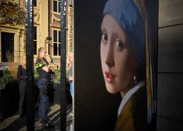 <p>A police officer (left) stands outside the Mauritshuis museum, where three people were arrested for attempting to smudge Vermeer's painting 'Girl with a Pearl Earring</p>