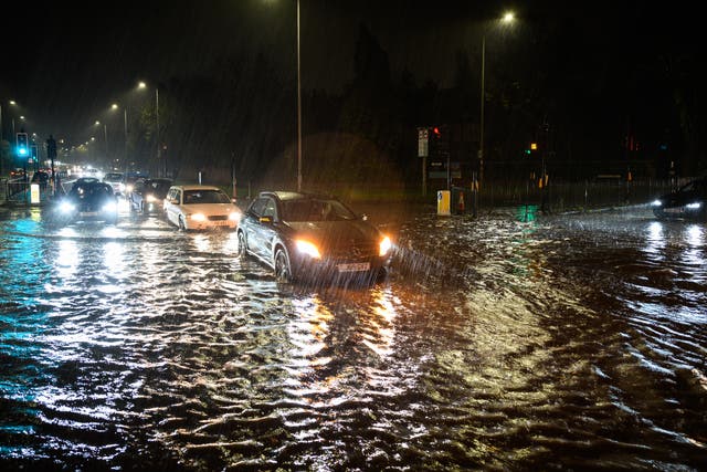 <p>Vehicles negotiate a flooded section of the A1 road in London on Wednesday night</p>