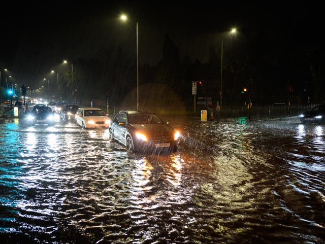 <p>Vehicles negotiate a flooded section of the A1 road in London on Wednesday night</p>