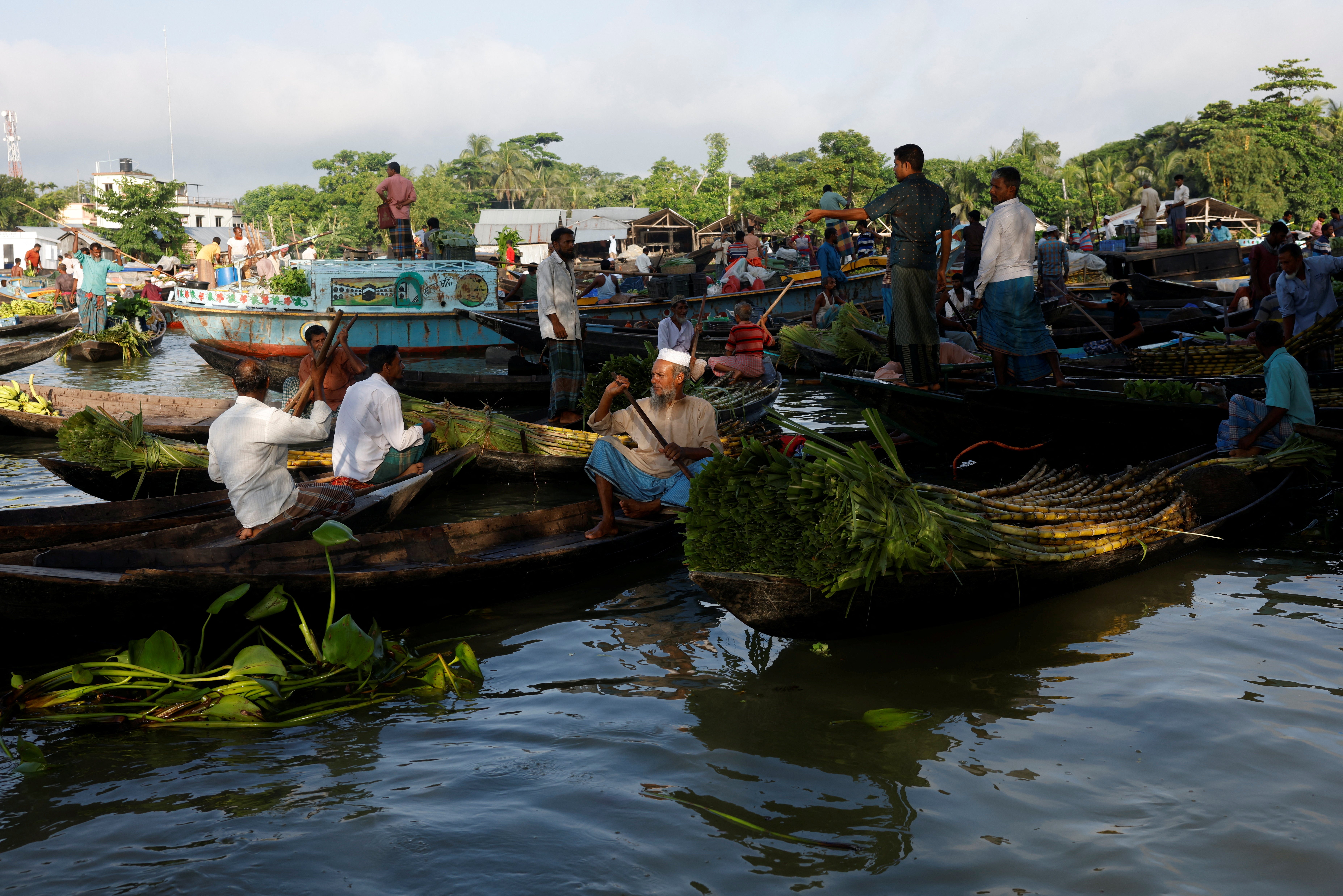 Farmers sell their vegetables, fruits and seedlings to middlemen at a biweekly floating market on the Belua river in Pirojpur