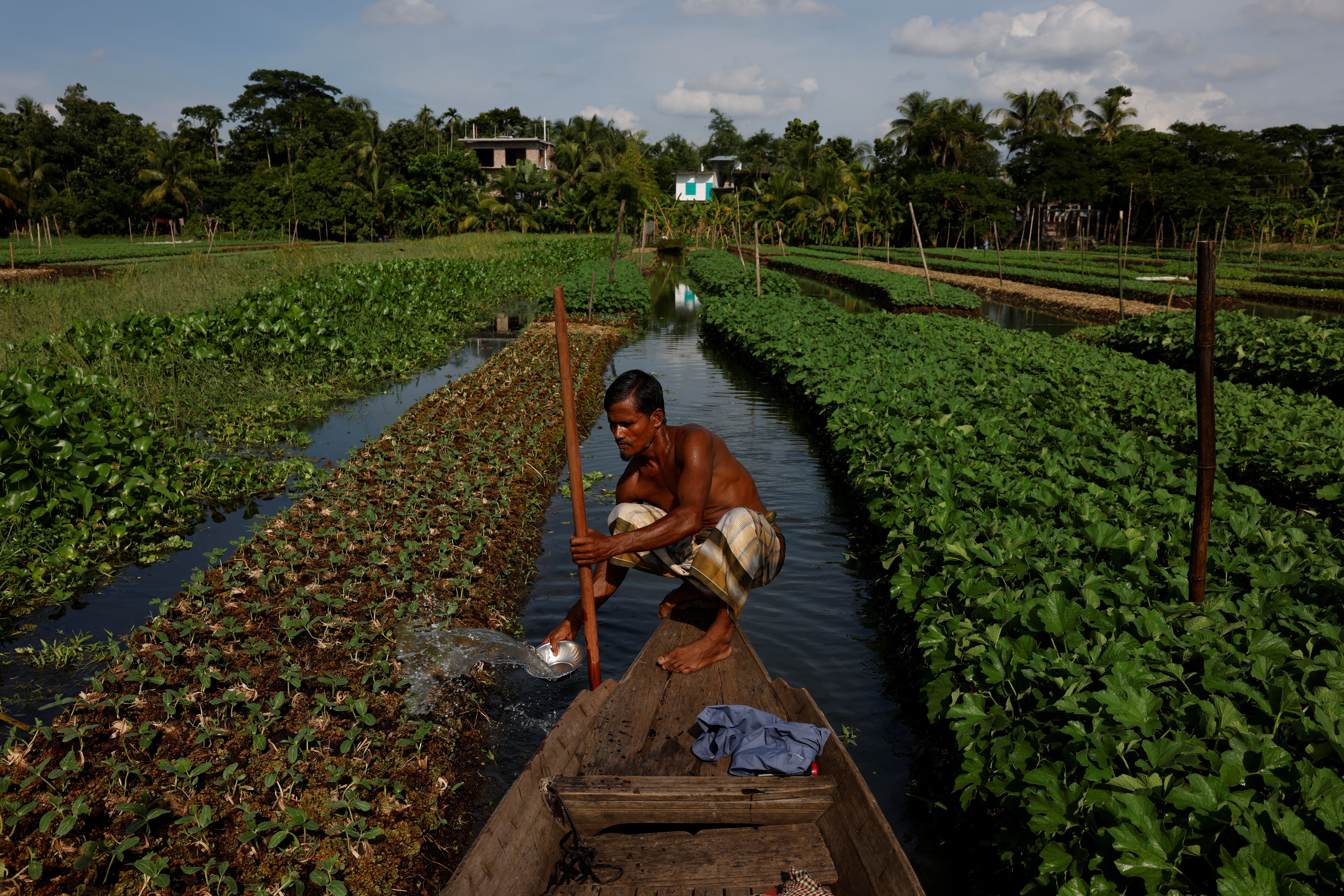 Mohammad Ibrahim, 48, irrigates his floating bed at his farm