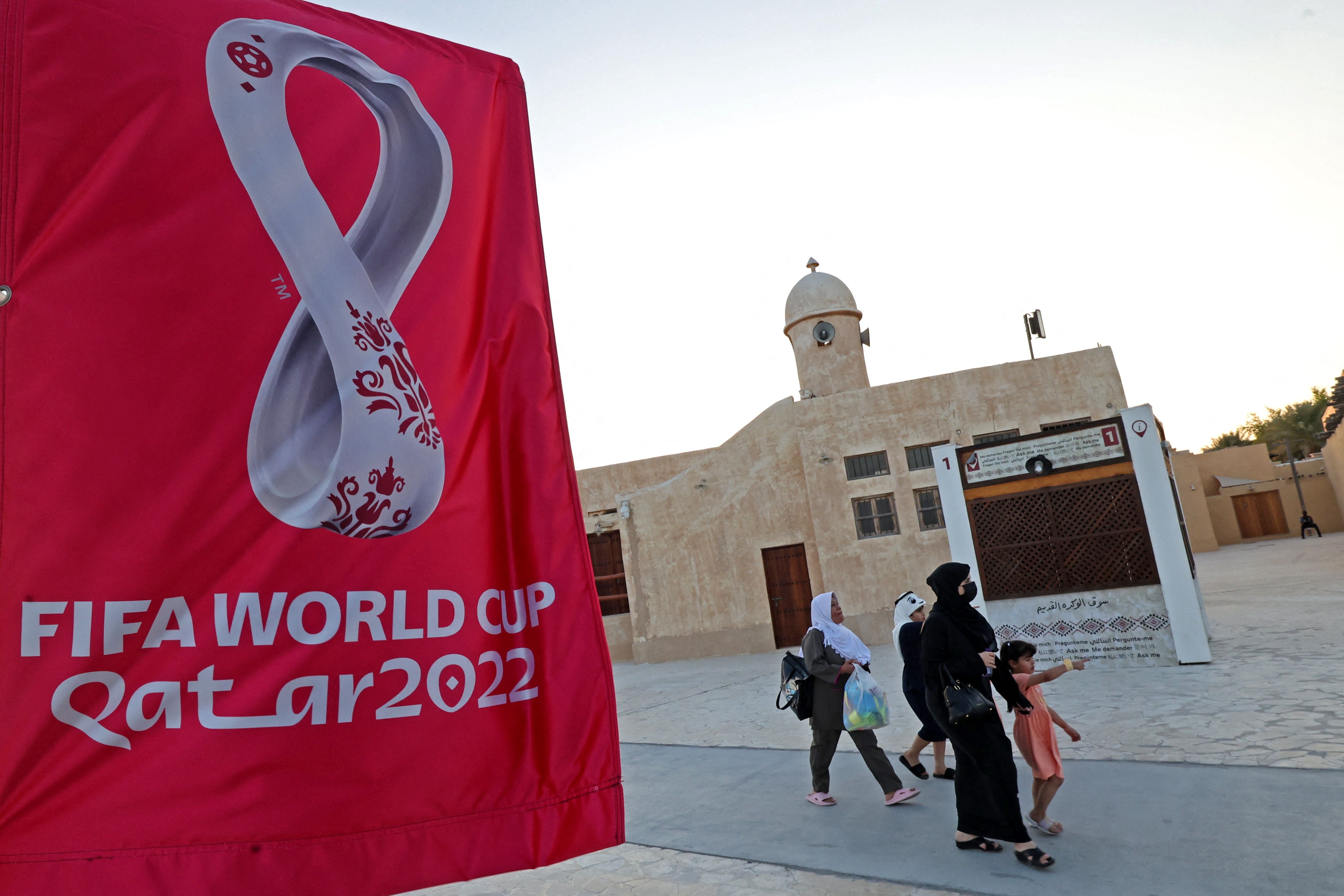 People walk past Fifa World Cup banners at a beach in Doha