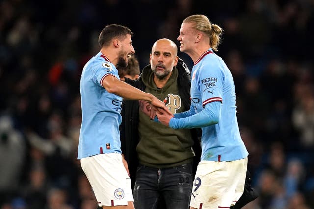 Erling Haaland, right, celebrates with team-mate Ruben Dias , left, and manager Pep Guardiola (Nick Potts/PA)