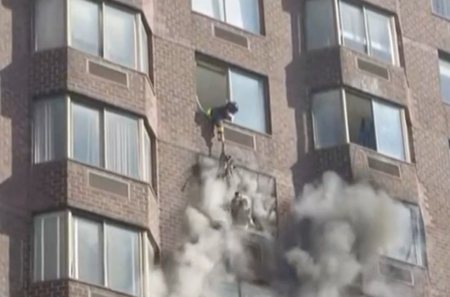 <p>Firefighters rescue a woman from a fire on the 20th floor of a Manhattan high-rise on 5 November 2022</p>