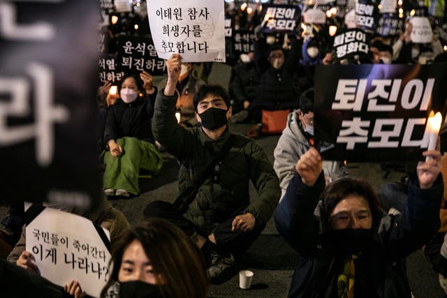 <p>People light candles holding a sign board demanding that President Yoon step down, during a memorial for the victims of Itaewon Halloween Stampede, near the city hall on November 05, 2022 in Seoul, South Korea</p>