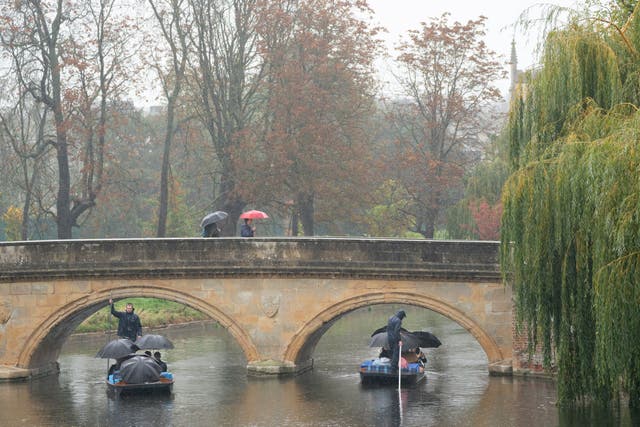 People shelter under umbrellas as they punt along the River Cam in Cambridge (Joe Giddens/PA)