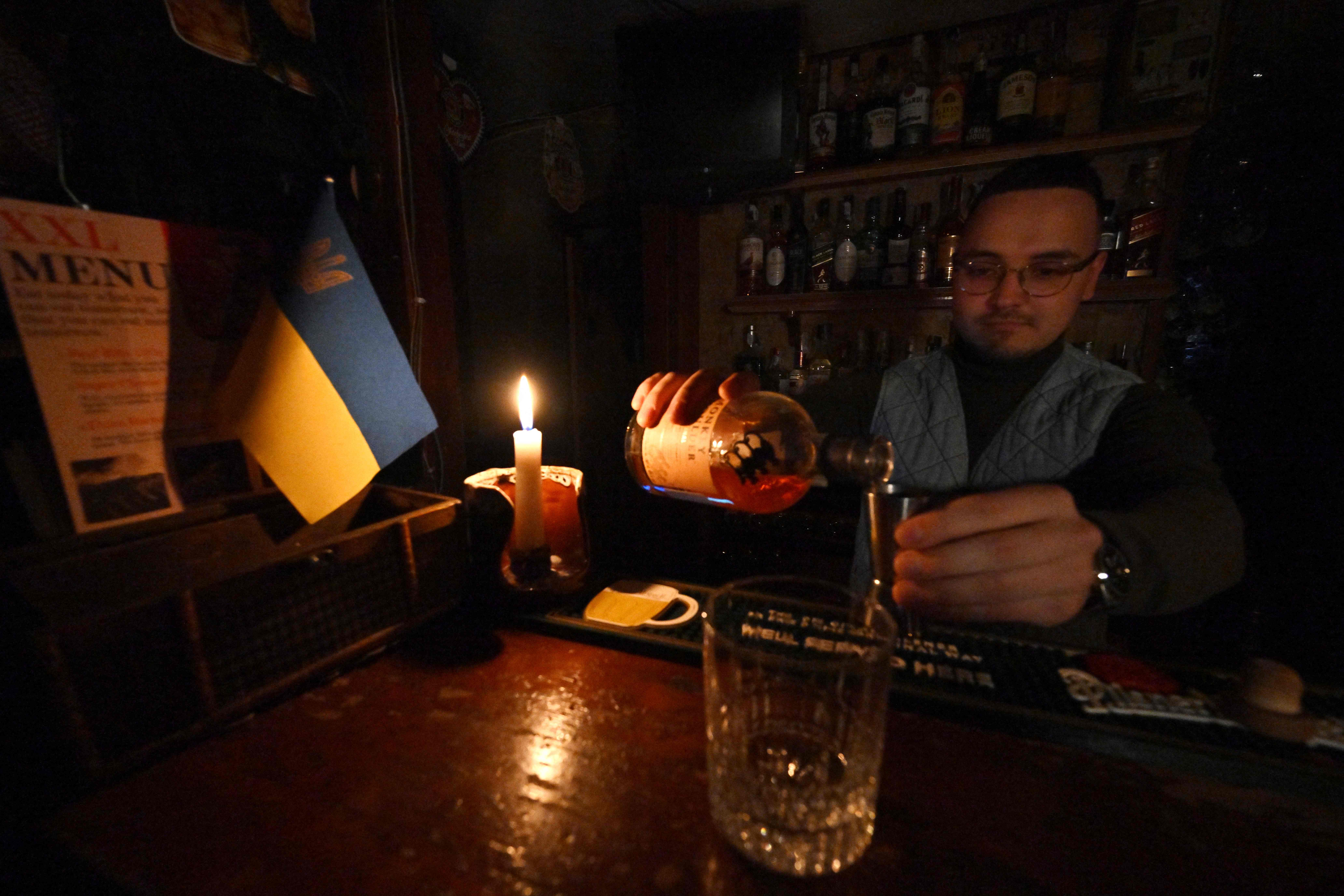 A bartender works in candlelight in Kyiv during a blackout in October
