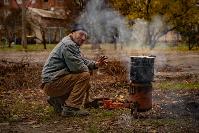 <p>A resident of Bakhmut cooks on a fire outside under shelling in the frontline town, which has little to no access to electricity or water</p>