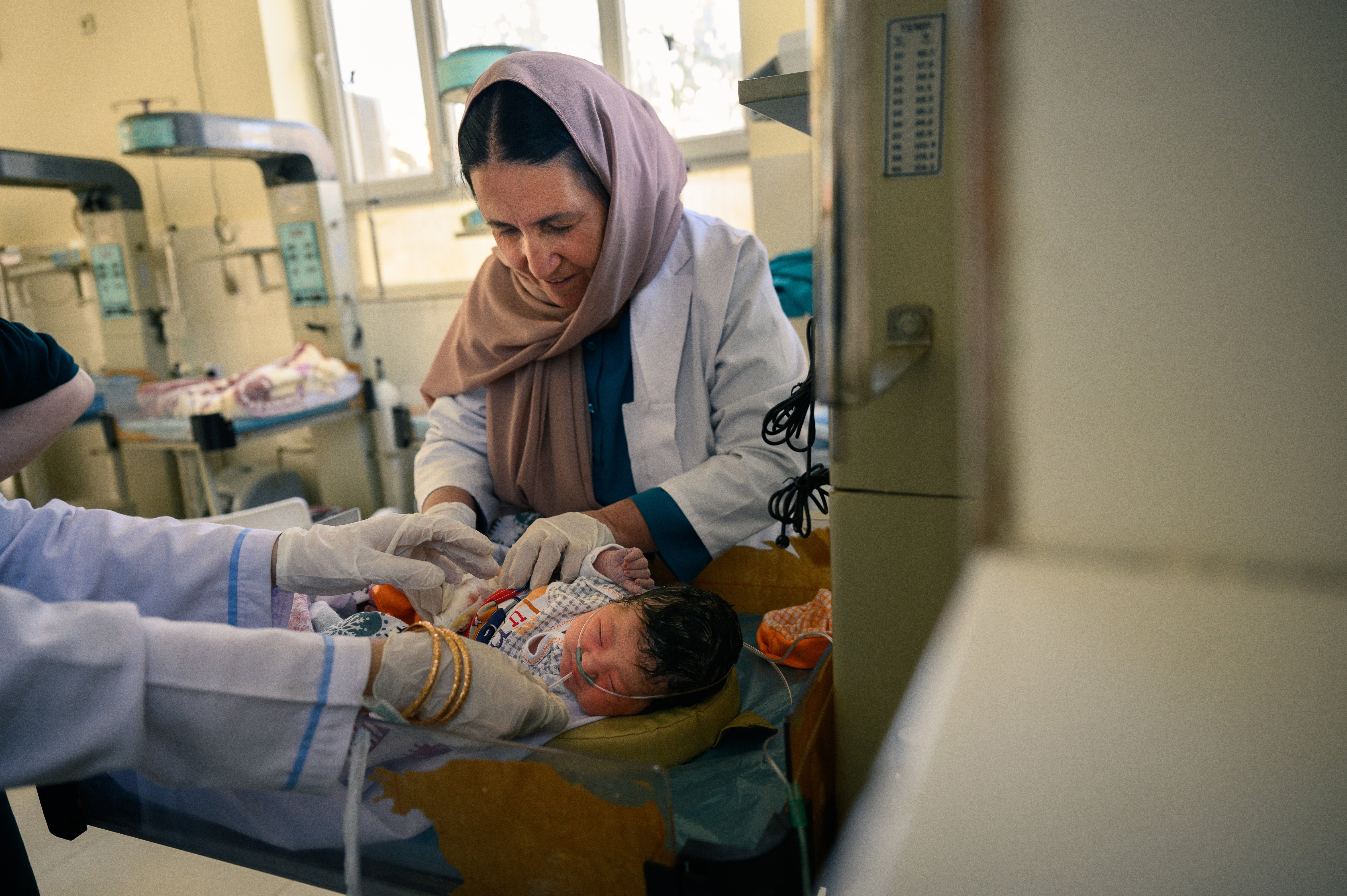 The chief of gynaecology tends to an infant in the neonatal ward