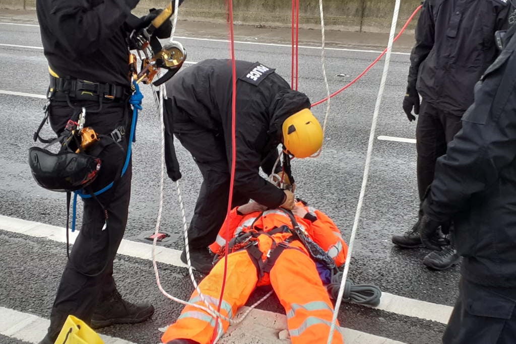 A Just Stop Oil protester being detained after they climbed a gantry on the M25, leading to the closure of part of the motorway on Monday