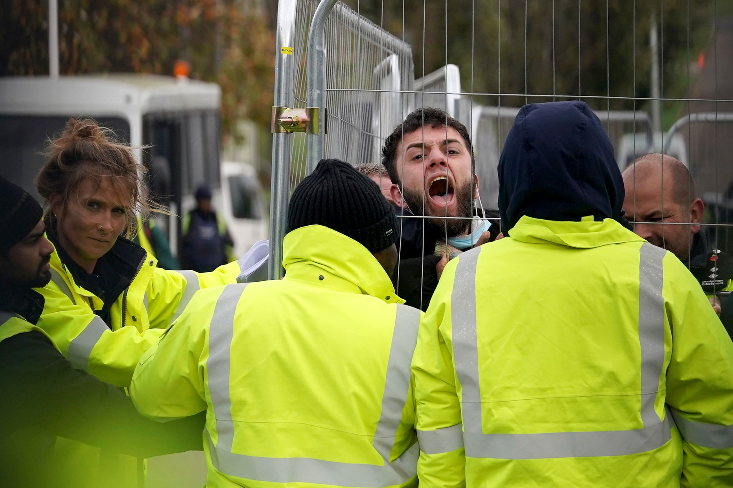 A migrant attempting to communicate with journalists is pinned against a fence by members of staff at the Manston immigration short-term holding facility in Kent (Gareth Fuller/PA)
