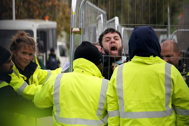 <p>A migrant attempting to communicate with journalists is pinned against a fence by members of staff at the Manston processing centre in Kent last month </p>