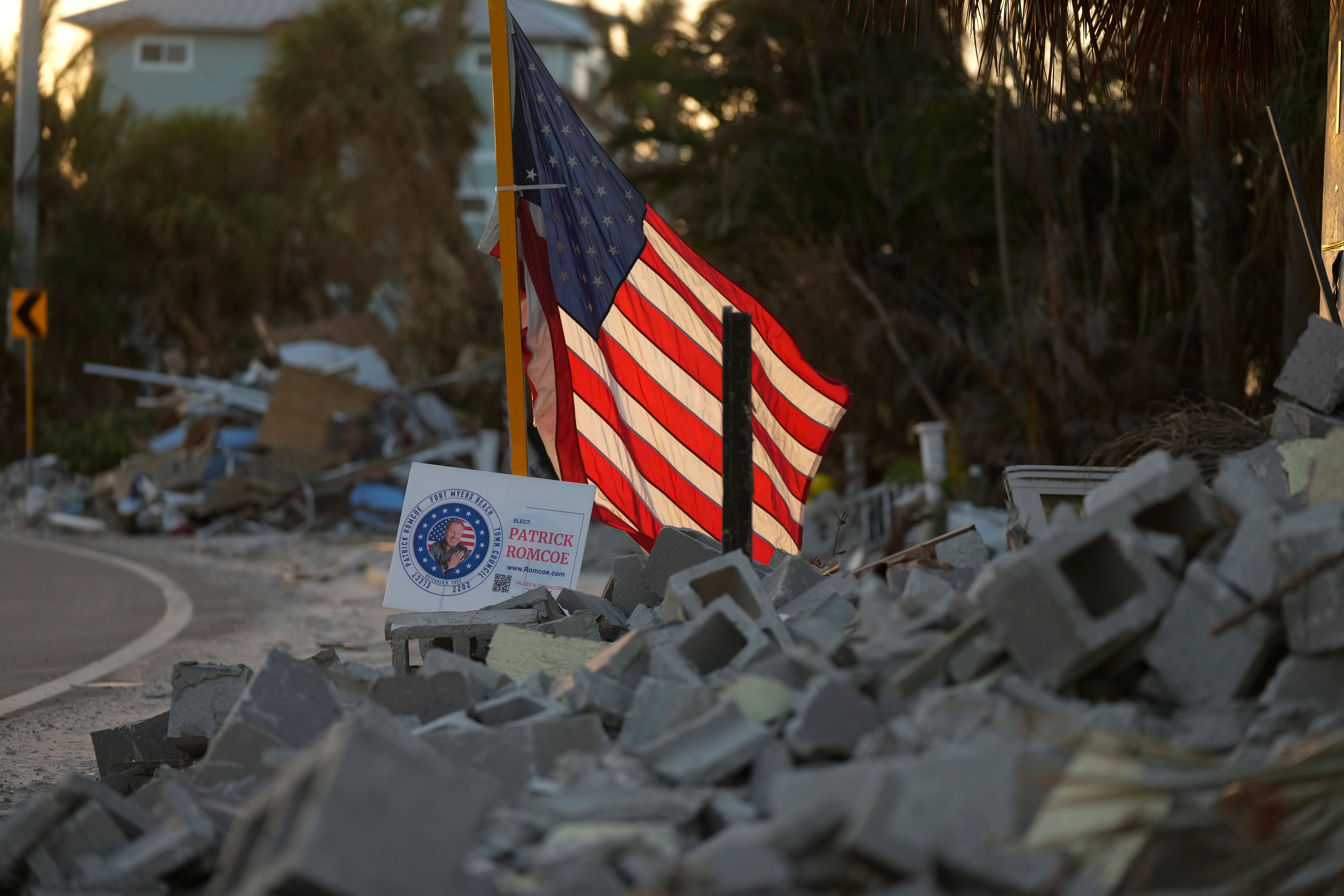 The American flag flies amid debris along a roadside on Estero Island, which was heavily damaged by Hurricane Ian in Fort Myers Beach, Florida