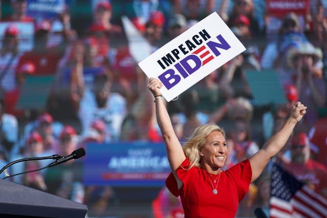 <p>Rep Marjorie Taylor Greene holds a sign that reads Impeach Biden at a rally featuring former US President Donald Trump on 25 September 2021 in Perry, Georgia</p>