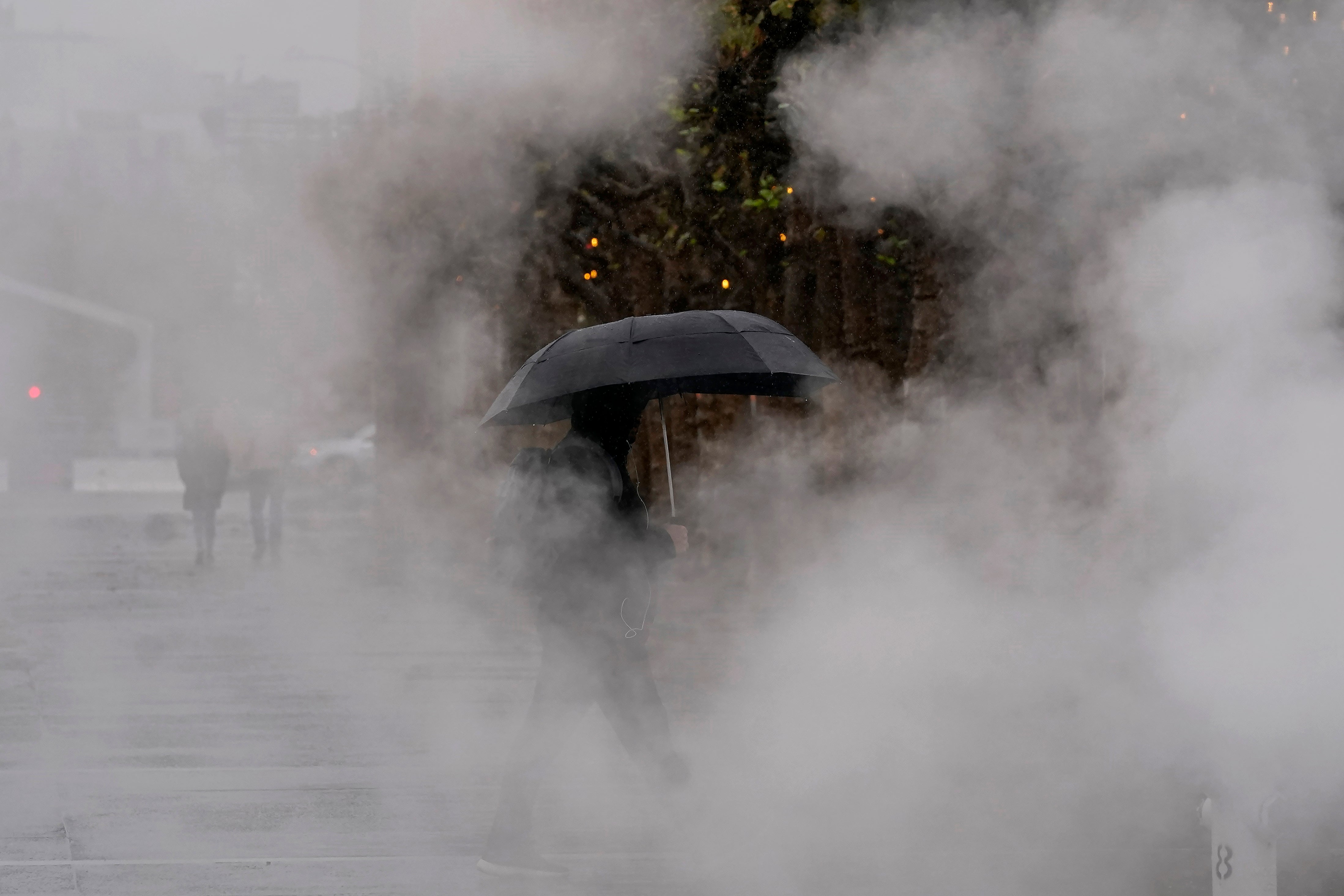 A pedestrian carries an umbrella while walking at Civic Center Plaza in San Francisco