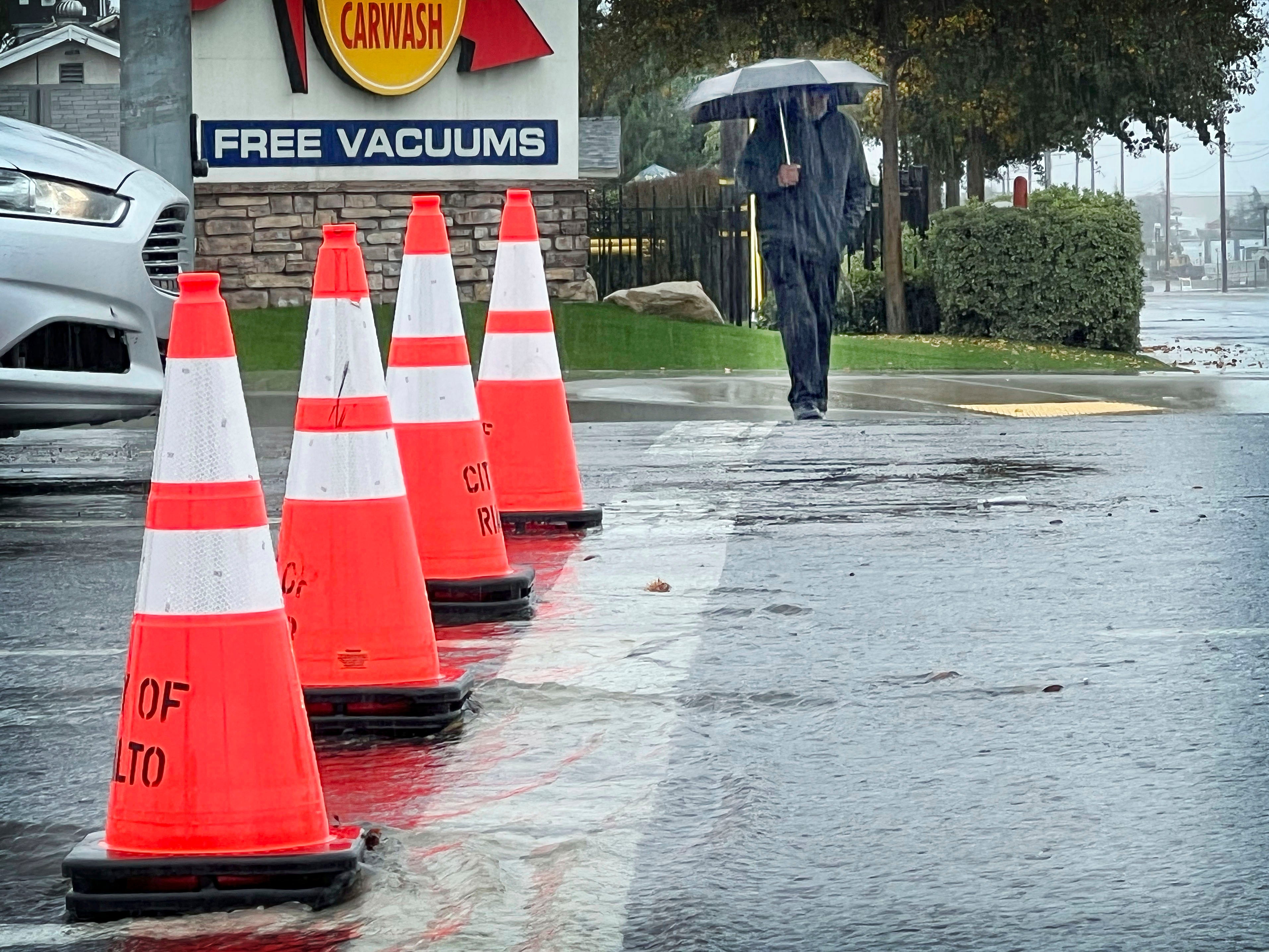 Larry Bernard Smith is protected from the rain as he crosses Foothill Blvd. on his way to get breakfast in Rialto, California