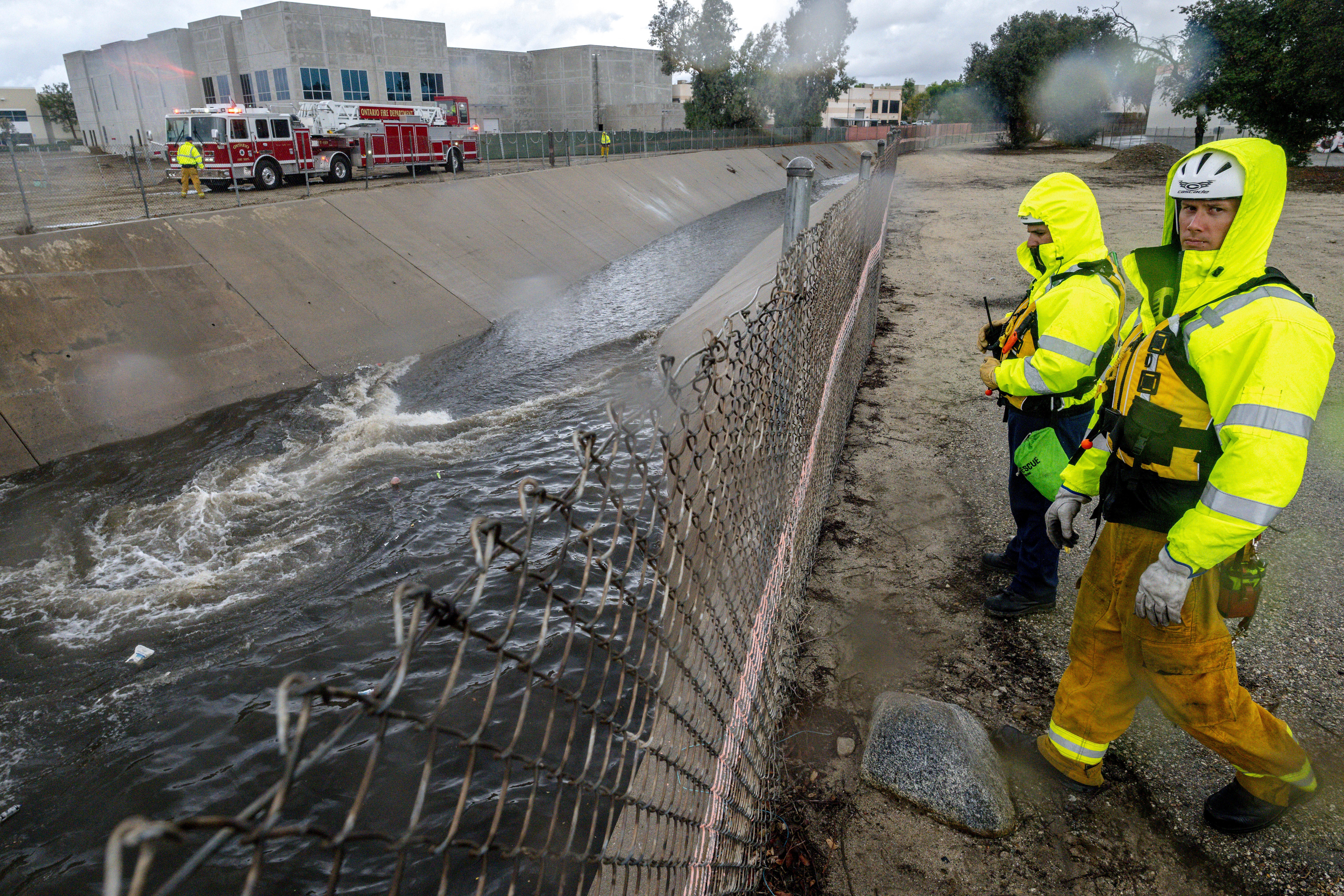 Firefighters look for people trapped in the rain-swollen Cucamonga wash in Ontario