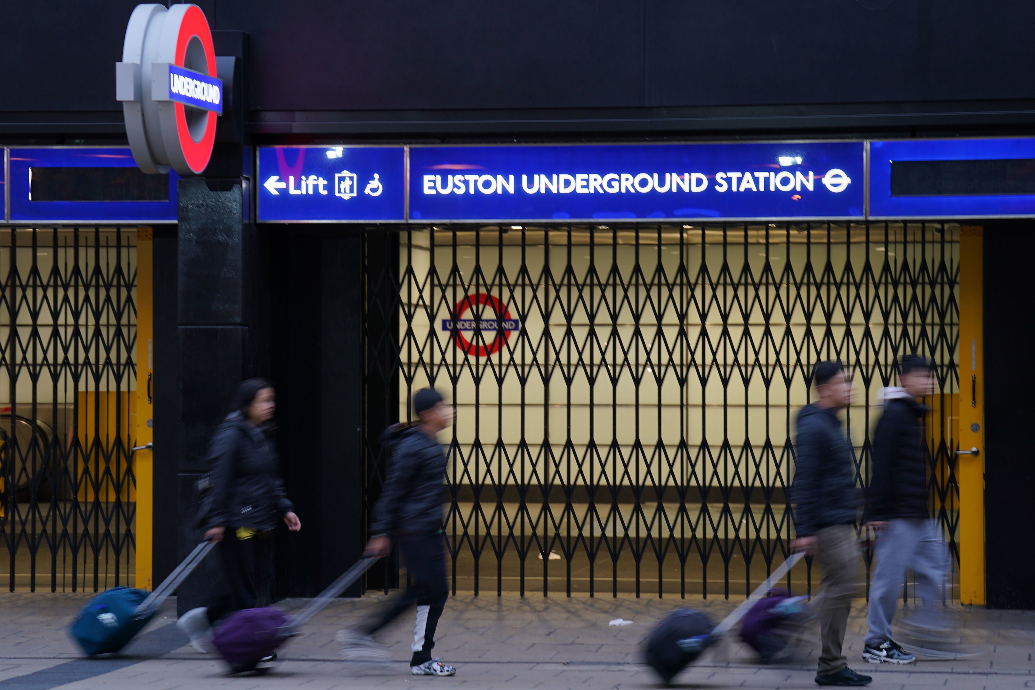 People walk past the closed shutters at the entrance to Euston underground station in central London,