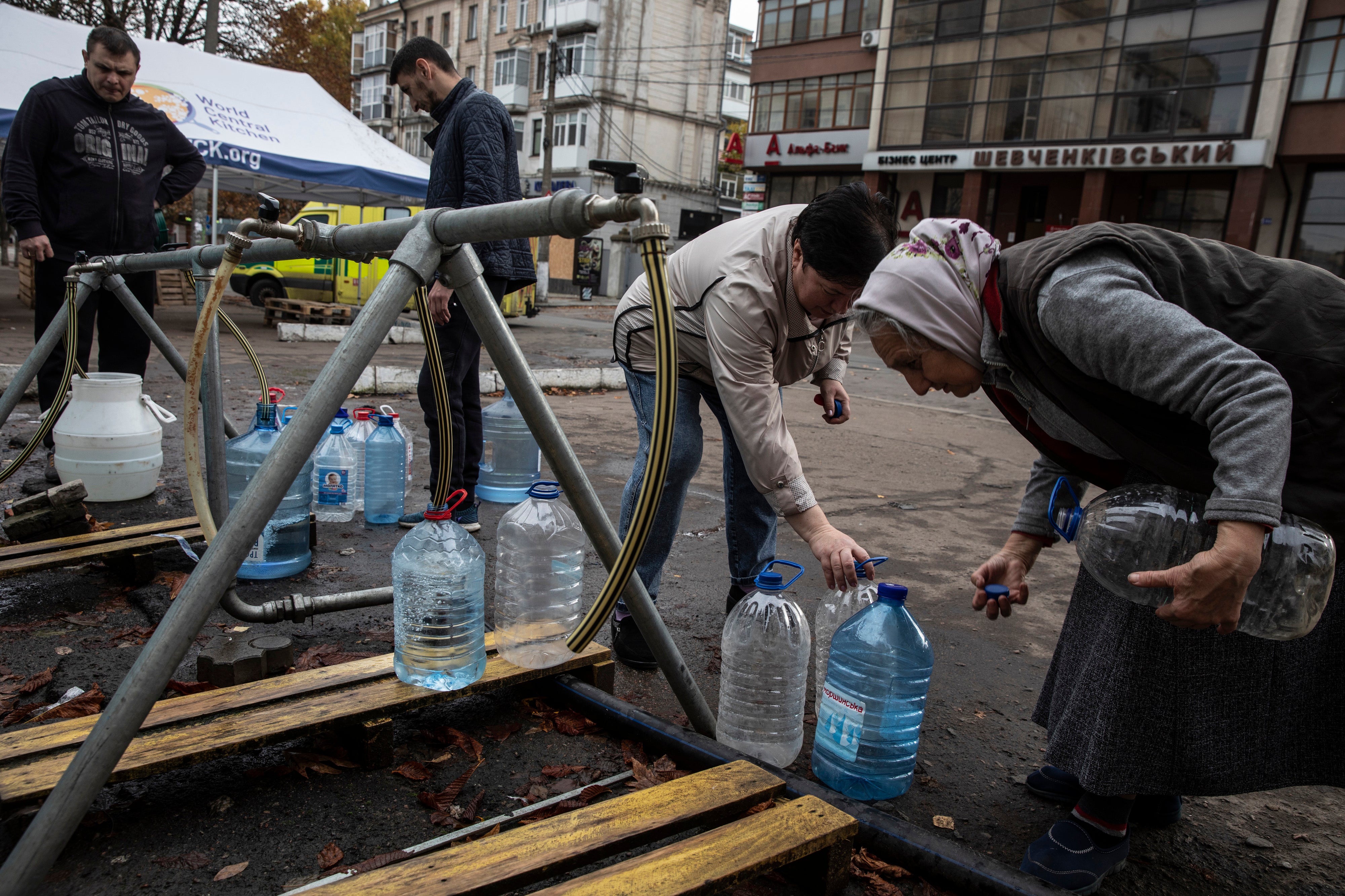 People fill plastic bottles with clean water at a humanitarian aid station in Mykolaiv