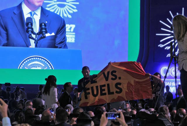 <p>Activists lift a banner which reads "People vs. Fossil Fuels"</p>