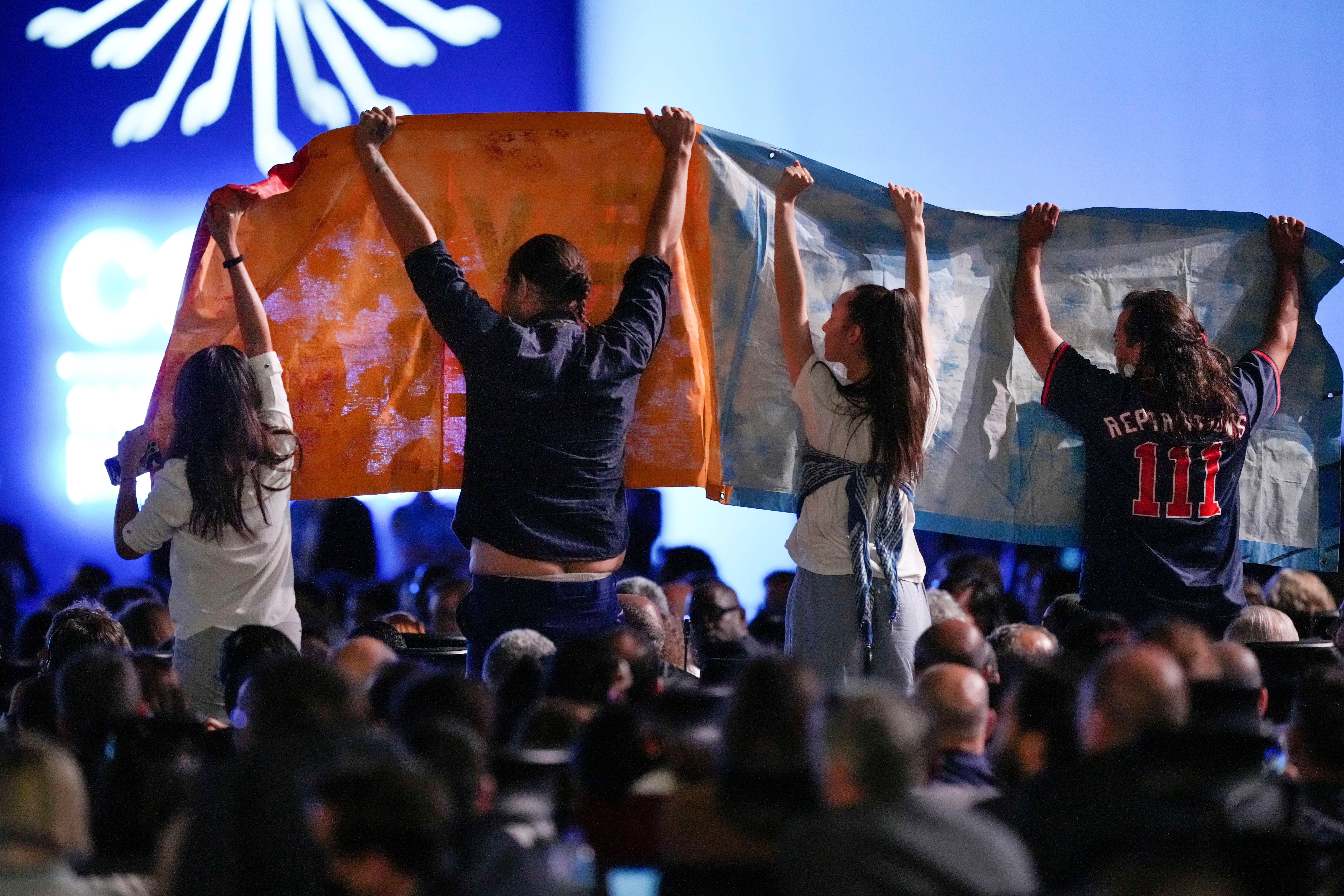 Protesters hold a banner as president Joe Biden speaks at Cop27