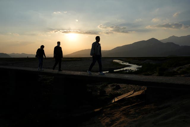 <p>FILE-Residents walk along a stretch of dried up Poyang Lake as the sun sets in north-central China’s Jiangxi province </p>