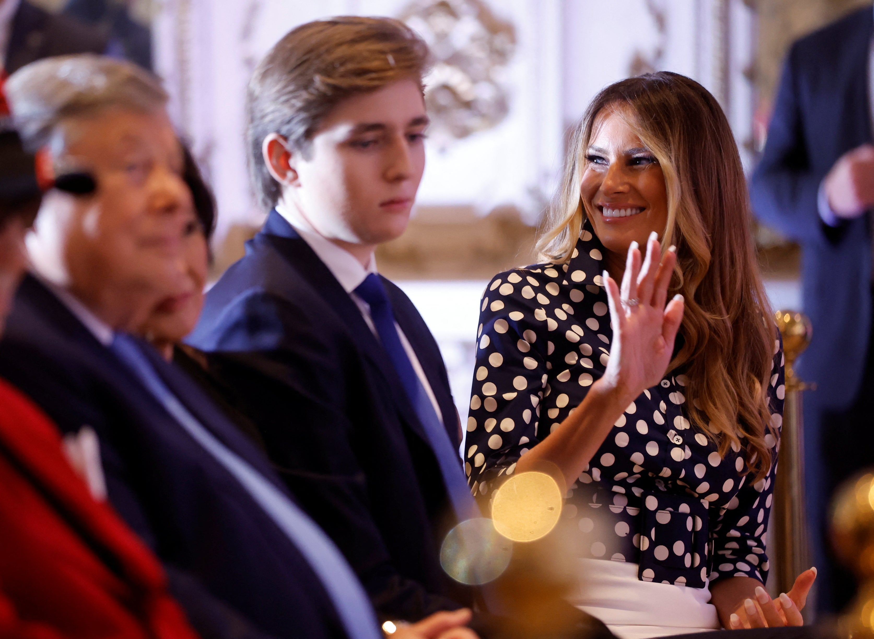 Melania Trump waves as she sits in the front row with their son Barron Trump and her parents as her husband announces that he will once again run for US president